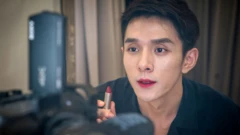 Li Jiaqi with his lips painted holds a lipstick