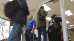 Security supervisors Franco Poerri (C) stands guard as students walk through metal detectors at William Howard Taft High School February 14, 2002 in Chicago, IL.