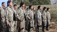 Ellerinde silahlar olan bir grup kadın ve erkek PKK üyesi. 