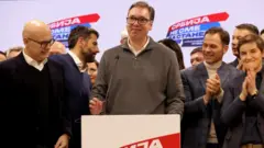Serbian President Aleksandar Vucic (C) arrives to address the media at the SNS election night after the Parliamentary and local elections in Belgrade