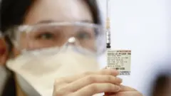 A health worker inspects a Pfizer syringe at a mass coronavirus disease (COVID-19) vaccination hub at the Showgrounds in Melbourne, Victoria, Australia, 19 July 2021
