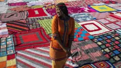 A performer stands in front of the thousands of knitted blankets on the school field at Steyn City to mark the upcoming Nelson Mandela Day as part of the 67 Blankets for Nelson Mandela Day project in Johannesburg, South Africa, 11 May 2021. The project sees thousands of blankets being knitted by "knitwits" and then given to those who need them during the cold winter in South Africa. Blankets are given away to those in need after the event. This year's event honored medical staff and first responders in the country for their work during the Covid-19 coronavirus crisis.