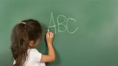 Imagem de banco de imagem de criança escrevendo em uma lousa