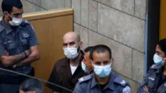 Palestinian Ayham Kamamji, 35, is surrounded by Israeli police officers as he appears at the magistrates' court in the northern Israeli city of Nazareth, on September 19, 2021