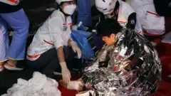 踐踏事故發生後，一名男子在現場接受救援隊成員的醫療救助。