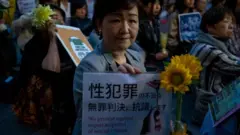 سيدة يابانية تمسك لوحة تطالب بتعزيز قوانين محاربة الجرائم الجنسية