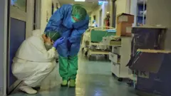 One hospital staff member consoles another in a corridor