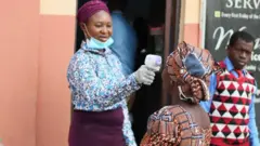 Usher dey check worshipper temperature before she enta church