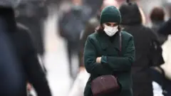A woman, wearing a protective mask, walks on Montorgueil street in Paris amid the coronavirus disease (COVID-19) outbreak in France, December 3, 2021.
