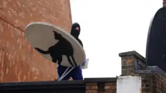 Muškarac sa fantomkom skida satelitsku antenu sa krova