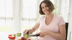 Une femme enceinte souriante prépare un déjeuner sain
