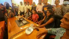 শ্রীলংকায় প্রেসিডেন্টে চেয়ারে বসে আছেন ক'জন বিক্ষোভকারী।
