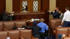 Capitol police point guns at a protester from inside the Senate chamber