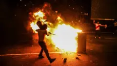 Manifestante tenta apagar um incêndio em Lima