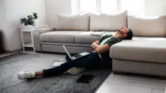 Homem deitado de braços cruzados em frente ao laptop