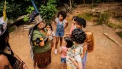 Mulher indígena conversa com grupo de crianças