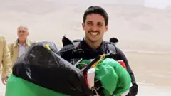 Jordanian Prince Hamzah bin al-Hussein, president of the Royal Aero Sports Club of Jordan, carries a parachute during a media event to announce the launch of "Skydive Jordan", in the Wadi Rum desert in April 2011