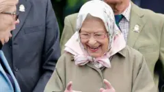 The Queen gesturing how close a horse race was to a fellow spectator