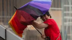 一名女性在颱風中舉傘逆風走在上海街頭