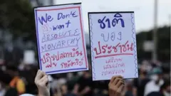 ผู้ชุมนุมกลุ่ม "ราษฎร" ถือป้ายระบุข้อเรียกร้องระหว่างเดินขบวนจากแยกสามย่านไปสถานทูตเยอรมนีเมื่อวันที่ 26 ต.ค.