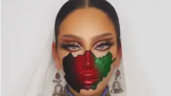 An Afghan female model with make-up of the Afghanistan flag painted on her face