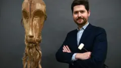 Le masque Ngil à côté du commissaire-priseur