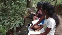 බදුරලිය ප්‍රදේශයේ පාසල් සිසුන් පිරිසක් මහමග ජාලගත අධ්‍යාපනයේ යෙදෙමින් සිටින අයුරු සමාජ ජලයේ සංසරණය වූ පිංතුරයක්