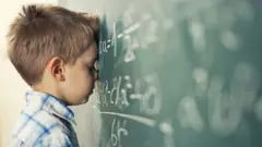 Young boy leans against chalkboard