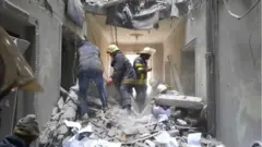 Bomberos en la oficina del gobernador de Járkiv, destrozada por un misil