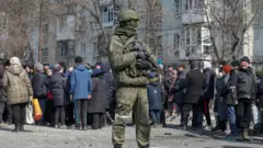 Российский солдат на фоне мирных жителей Маруиполя