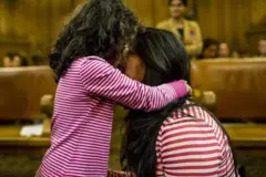 Criança abraça mulher adulta em sala de julgamento