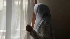 camdan bakan bir afgan kadın