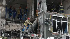 Equipes de resgate ucranianas trabalham no local atingido por um ataque russo contra um prédio residencial de vários andares em Kiev, na Ucrânia