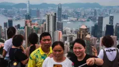 Turistas en Victoria Peak en Hong Kong posan para selfies y admiran la vista del puerto Victoria