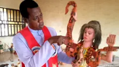 Reverend Paul Obayi holds an idol