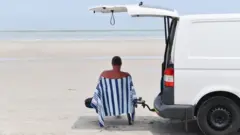 Man sits in the shade on a beach in Adelaide, Australia