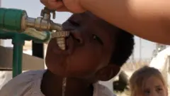 Child drinking from a water tap