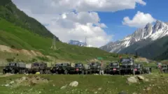 Indian army soldiers walk past their parked trucks at a makeshift transit camp before heading to Ladakh, near Baltal, southeast of Srinagar,16 June 2020