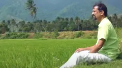 Sridhar sitting near a paddy field