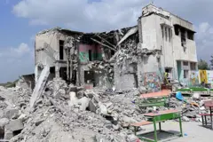 Развалины здания, возле которого стоят школьные парты.