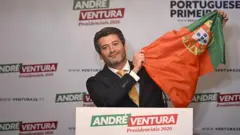 André Ventura levantando uma bandeira de Portugal.