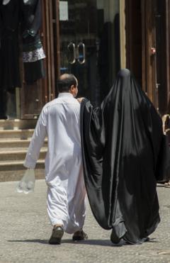 Una pareja saudita camina por las calles de Al Balad, están vestidos con la vestimenta tradicional.