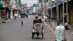 An elderly handicapped man rides his wheelchair on a deserted street in Jaffna city in the Norther province of Sri Lanka on 13 Friday October 2017