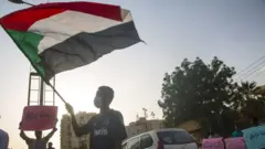 Man waves a Sudanese flag in Khartoum (file photo)