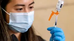 a nurse loads a syringe with vaccine
