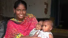 जुळ्या मुलांसोबत महिला