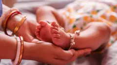 Majka drži u rukama bebina stopala