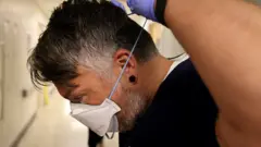 Profissional de saúde ajustando máscara N95/PFF2 atrás da cabeça