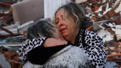 A woman reacts while embracing another person, near rubble following an earthquake in Hatay, Turkey, February 7, 2023