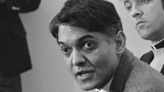 Eqbal Ahmad, (L) is shown as a spokesman for Father Philip Berrigan, where he told newsmen that Berrigan dismissed Ramsey Clark as his attorney in the Harrisburg 7 Trial that opened here. Berrigan had asked to make an opening statement, but was denied by the judge. When asked to defend himself for being denied, he explained that he considered himself without counsel. Left to right is Ahmad, Reverend Neil McLaughlin, and former priest Anthony Scoblick.